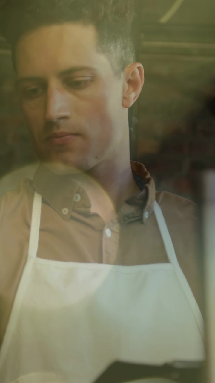 Video verticale: Barista che si allunga e regola il rubinetto in un caffè, con indicatori animati per l'ordine.