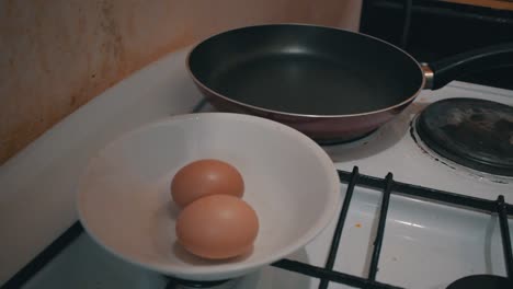 two eggs in a bowl on a stove next to the frying pan