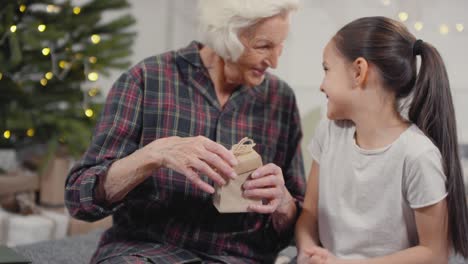 nonna felice che apre il regalo di natale dalla nipotina e la abbraccia