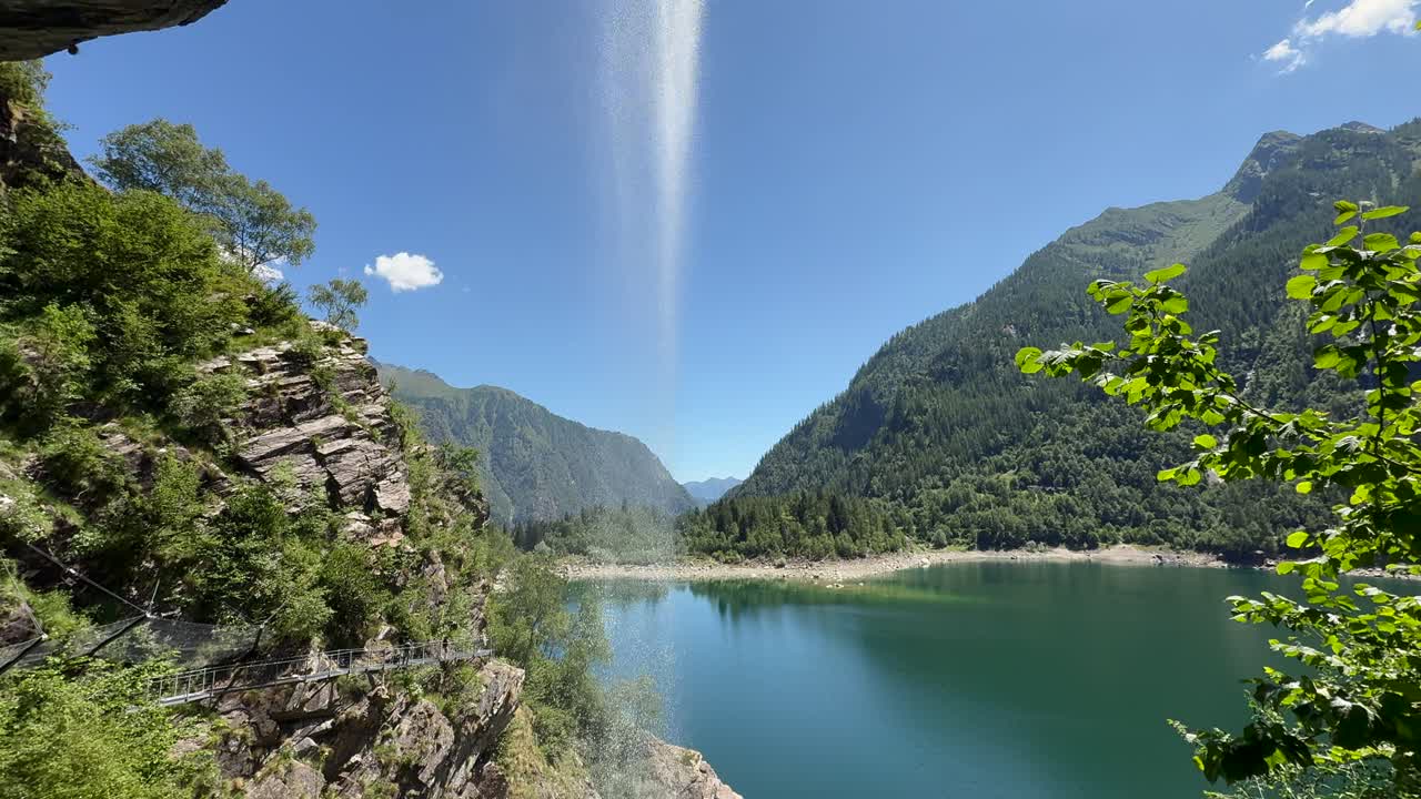 Cascata che si innalza dal Lago di Antrona, circondata da montagne e un cielo sereno