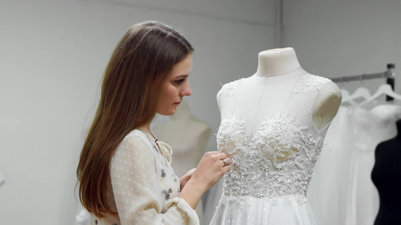 Portrait of a girl creating a wedding dress by exclusive order sewing fabrics and rhinestones on a dress dressed in a mannequin. production of wedding dresses. Little business