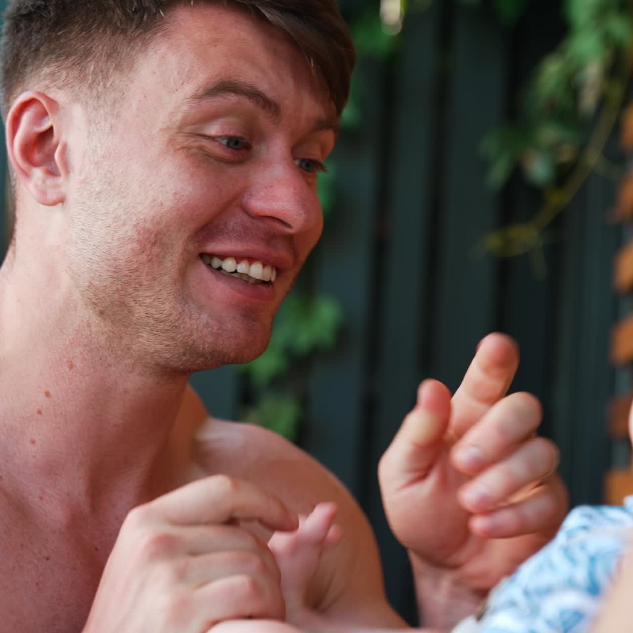 Caucasian father playing with his cute infant. Happy dad smiling to a baby and puts kid's feet on the face. Close up