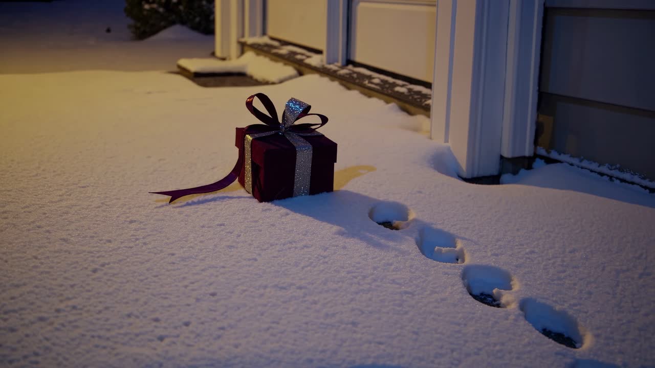 Mysterious gift box on snowy doorstep with footprints