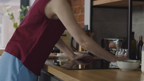 primer plano de una chica caucásica limpiando la cocina de inducción