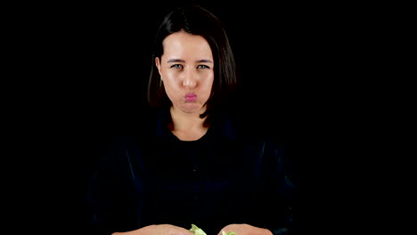 young woman eating cabbage leaf, healthy vegan food concept, black background