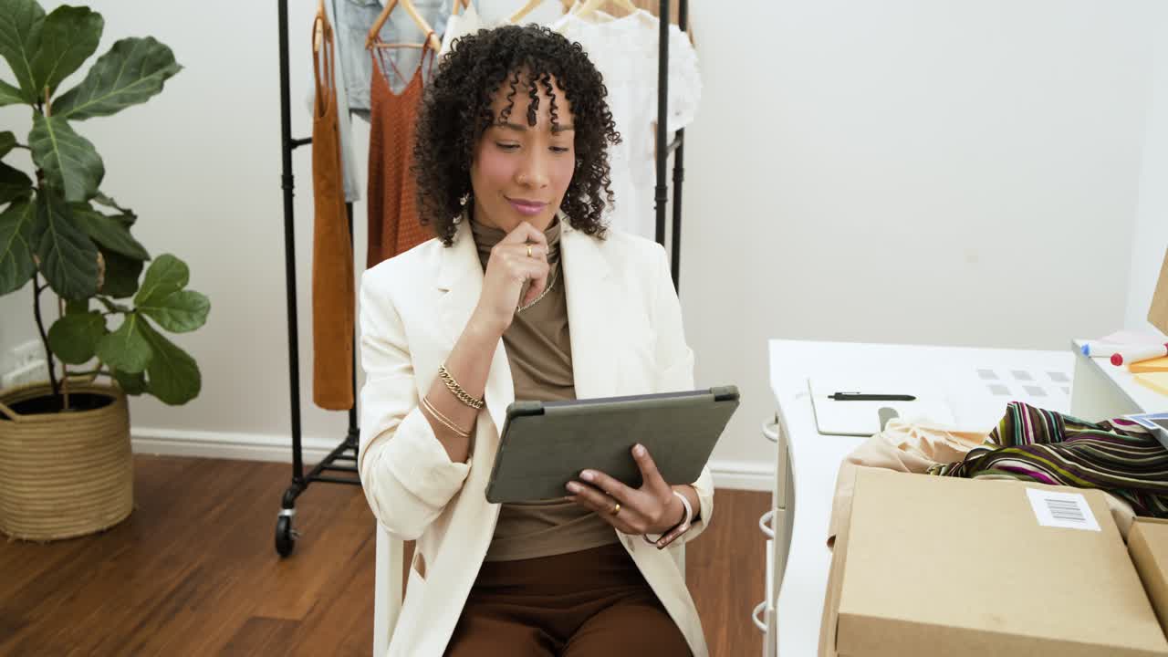 Woman lifting index finger as idea forms, tapping and scrolling tablet in studio reviewing fabric