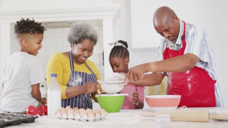Smiling-african-american-grandparents-baking-with-granddaughter-and-grandson,-in-slow-motion