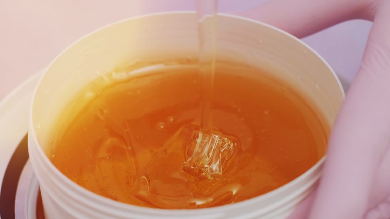 Liquid sugar for skin epilation. Close up shot. depilation and beauty concept - sugar paste or wax honey for hair removing with wooden waxing spatula sticks