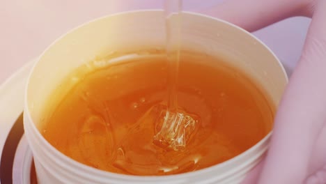 liquid sugar for skin epilation. close up shot. depilation and beauty concept - sugar paste or wax honey for hair removing with wooden waxing spatula sticks