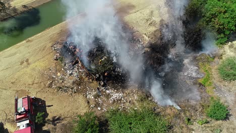 vista aerea di un vigile del fuoco che cerca di calmare un incendio in un edificio, fumo che sale in un fiume in campagna, del messico, america centrale - statico, colpo di drone