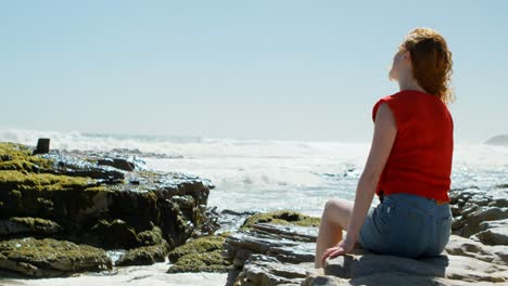 Woman-sitting-on-a-rock-and-looking-at-the-ocean-4k