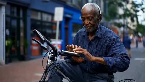 senior man using tablet on a bicycle in the city
