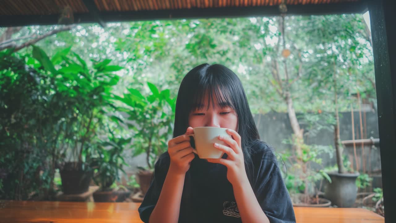 A Serene Moment of Reflection: A Young Person Enjoys a Warm Cup of Tea Surrounded by Lush Greenery in a Cozy Setting