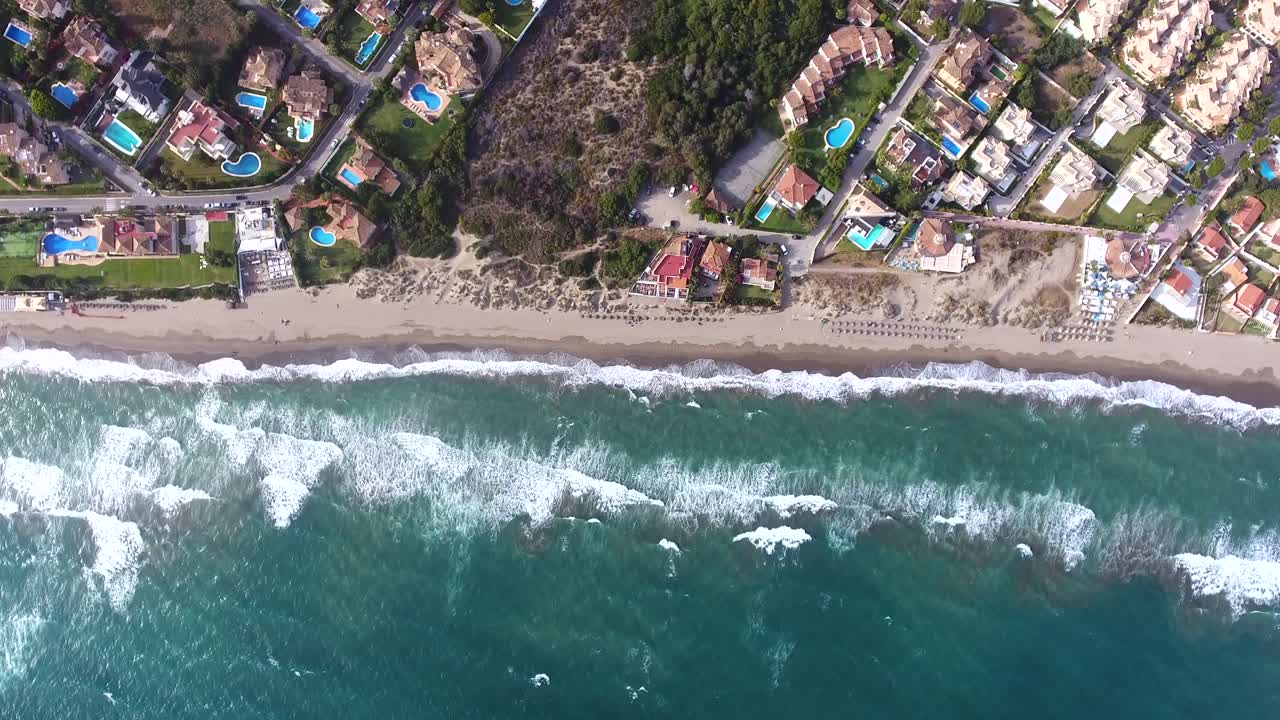 vista aérea desde lo alto mirando las olas rompiendo en la costa española, vista de la playa de verano desde lo alto del cielo filmada desde un dron de 4k