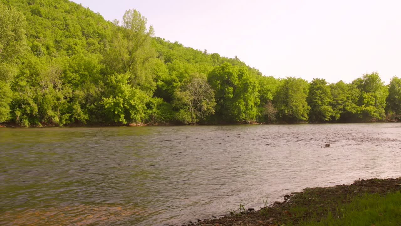 Fiume Dordogna calmo sotto cieli soleggiati vicino a lussureggianti colline verdi in Francia.