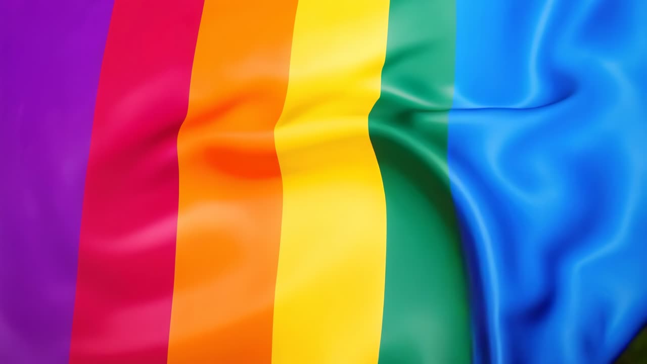 Färgstark regnbågsflagga som vajar i vinden, fångad från en låg vinkel.