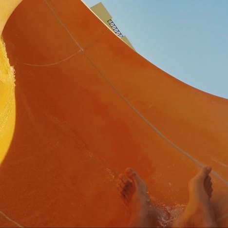 a man descends from a water slide with only feet visible