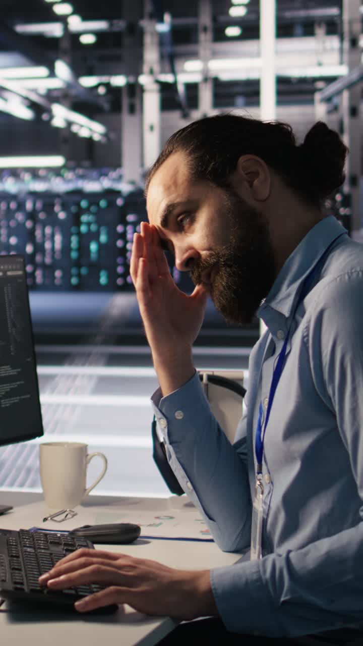Vertical video Exhausted computer scientist in server room suffering from mental fatigue