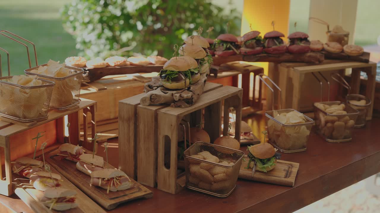 Gourmet mini burgers and appetizers arranged on wooden boards for outdoor catering event
