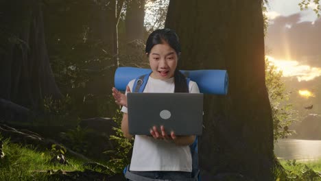 asian female hiker with mountaineering backpack looking at a laptop and saying wow while exploring forest nature