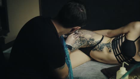 artista del tatuaje trabajando en el tatuaje de cadera de una mujer