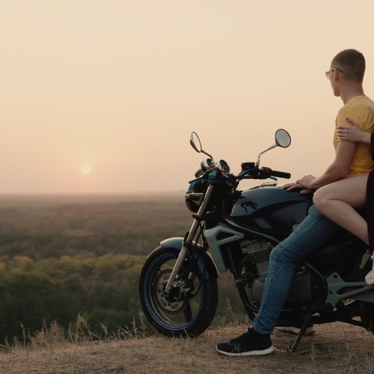 pareja romántica sentada en una motocicleta y admirando la puesta de sol 2