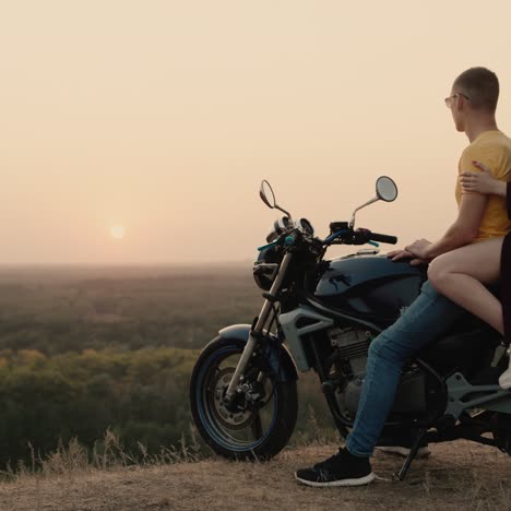 pareja romántica sentada en una motocicleta y admirando la puesta de sol 2
