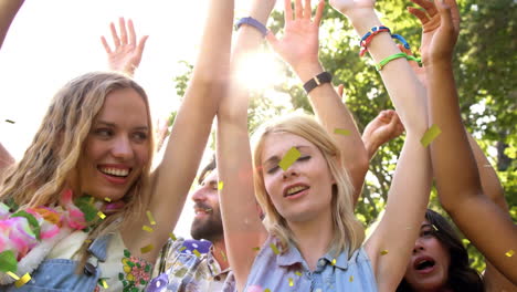 animation of gold confetti falling over happy people dancing outdoors