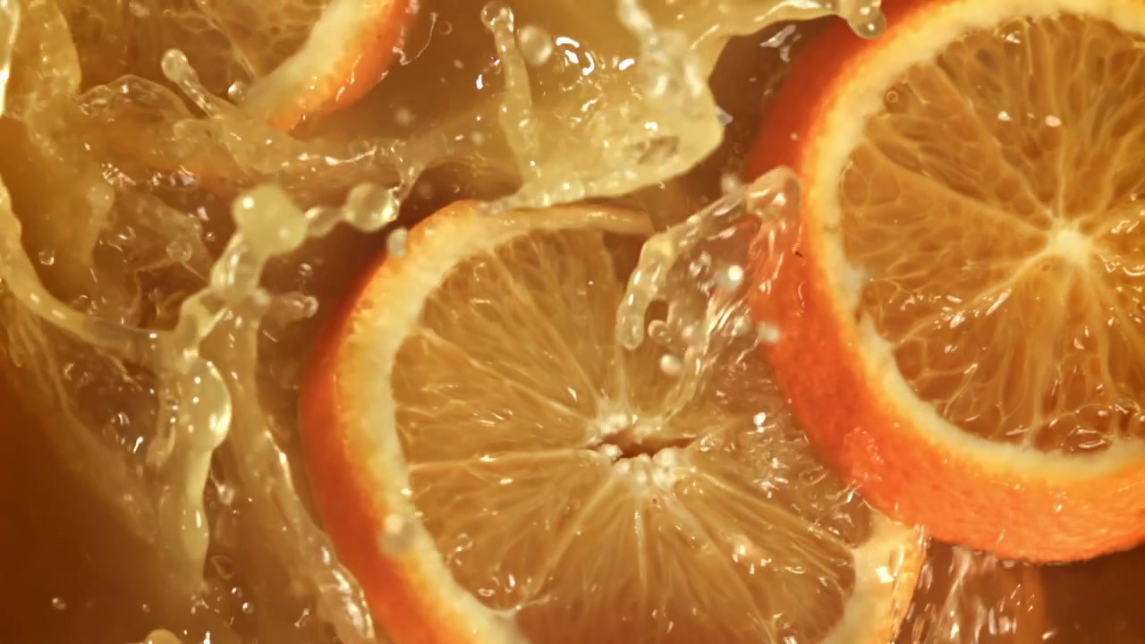 Fette d'arancia che schizzano nel succo fresco al rallentatore