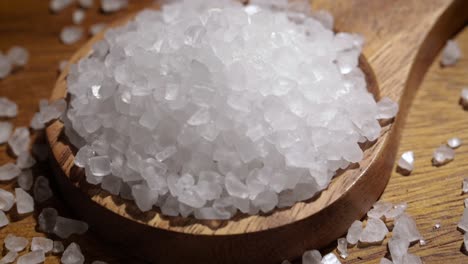 cristales de sal marina de cerca en una cuchara de madera en una mesa de la cocina.