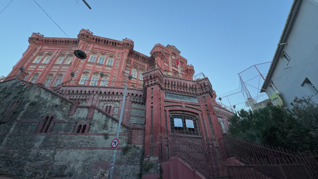 A low-angle, 4K cinematic footage captures the majestic structure of the historic Phanar Greek Orthodox College (Φαναριώτικη Μεγάλη του Γένους Σχολή) in Istanbul, Turkey, often referred to as 'The Red