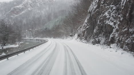 Conduciendo-A-Lo-Largo-De-Un-Río-En-Una-Peligrosa-Carretera-De-Cañón-Helado-Con-Fuertes-Nevadas