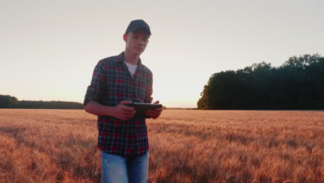 propositivo contadino maschio va sulla strada tra i campi di grano al tramonto
