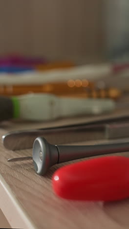 una vista de cerca de una variedad de herramientas ordenadamente dispuestas en un banco de trabajo de madera, las herramientas incluyen destornilladores, pinzas y otros instrumentos de precisión