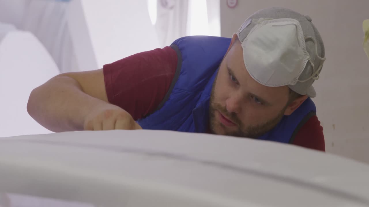 un hombre que hace tablas de surf en su taller