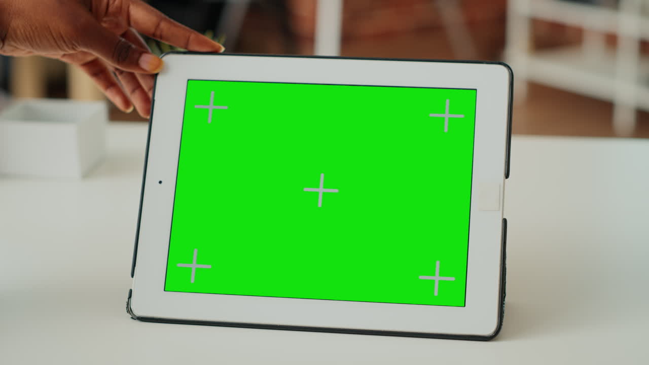 Young woman holding device with horizontal green screen