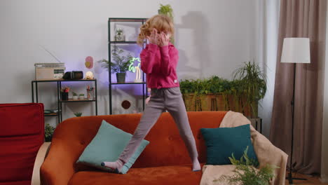 Funny-young-child-girl-kid-dancing-trendy-social-media-dance-while-listening-to-the-music-at-home