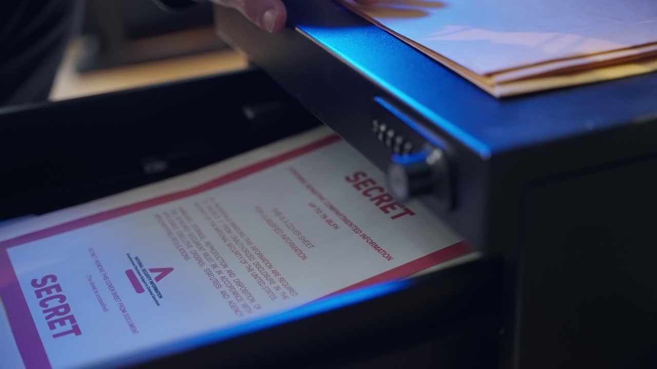 Person stealing classified file folder from office drawer at night. Man taking manila envelope with red label marked as secret for sensitive confidential material and information. Spy agent or a thief