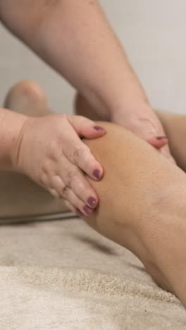 masseuse performing relaxing leg massage. vertical