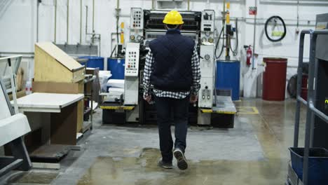 back view of printing worker walking at factory