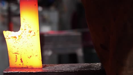 blacksmiths forging hot metal with hammer in workshop