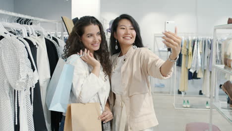 two women taking a selfie in a clothing store