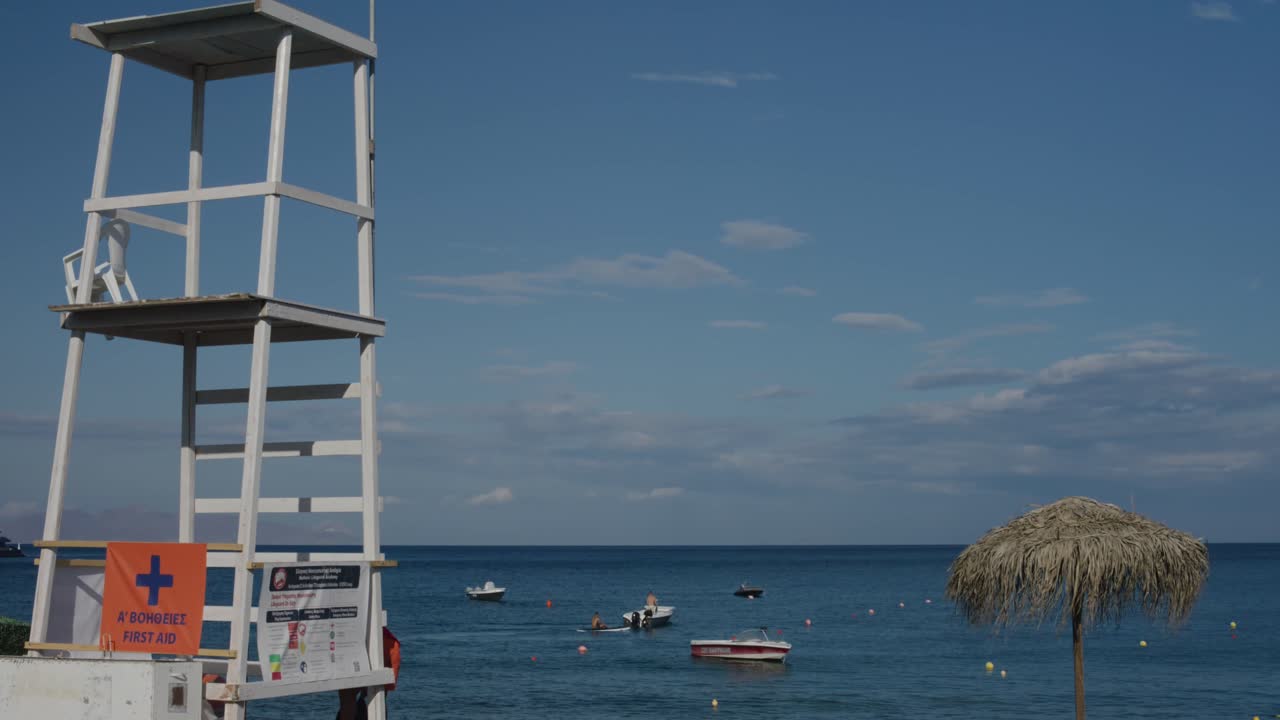 Tall life guard tower on beach as people use boats in the background in Santorini, Greece