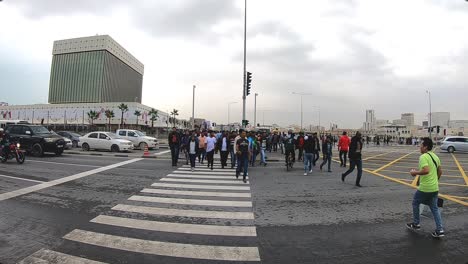 people crossing road using zebra crossing. doha is capital city of qatar and major part ofpopulation is expatriates here.