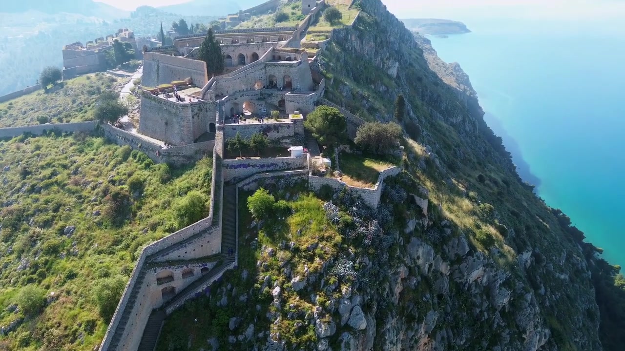 Splendida vista aerea 4K con drone delle famose scale di pietra a zigzag del Castello di Palamidi a Nauplia, Grecia. Salendo lungo la scogliera scoscesa per rivelare il centro storico della fortezza veneziana