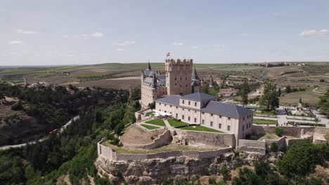 aerial view circling the alcazar of segovia medieval castle fortress standing on top of rocky crag overlooking spanish old city landscape