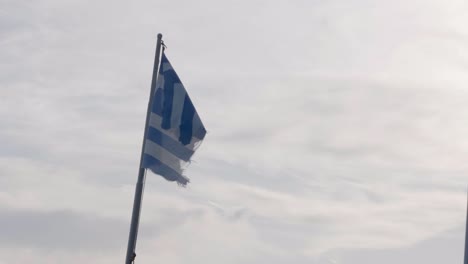 A Greece flag in a not so good condition, waving in the wind. The flag was hoisted on a boat.