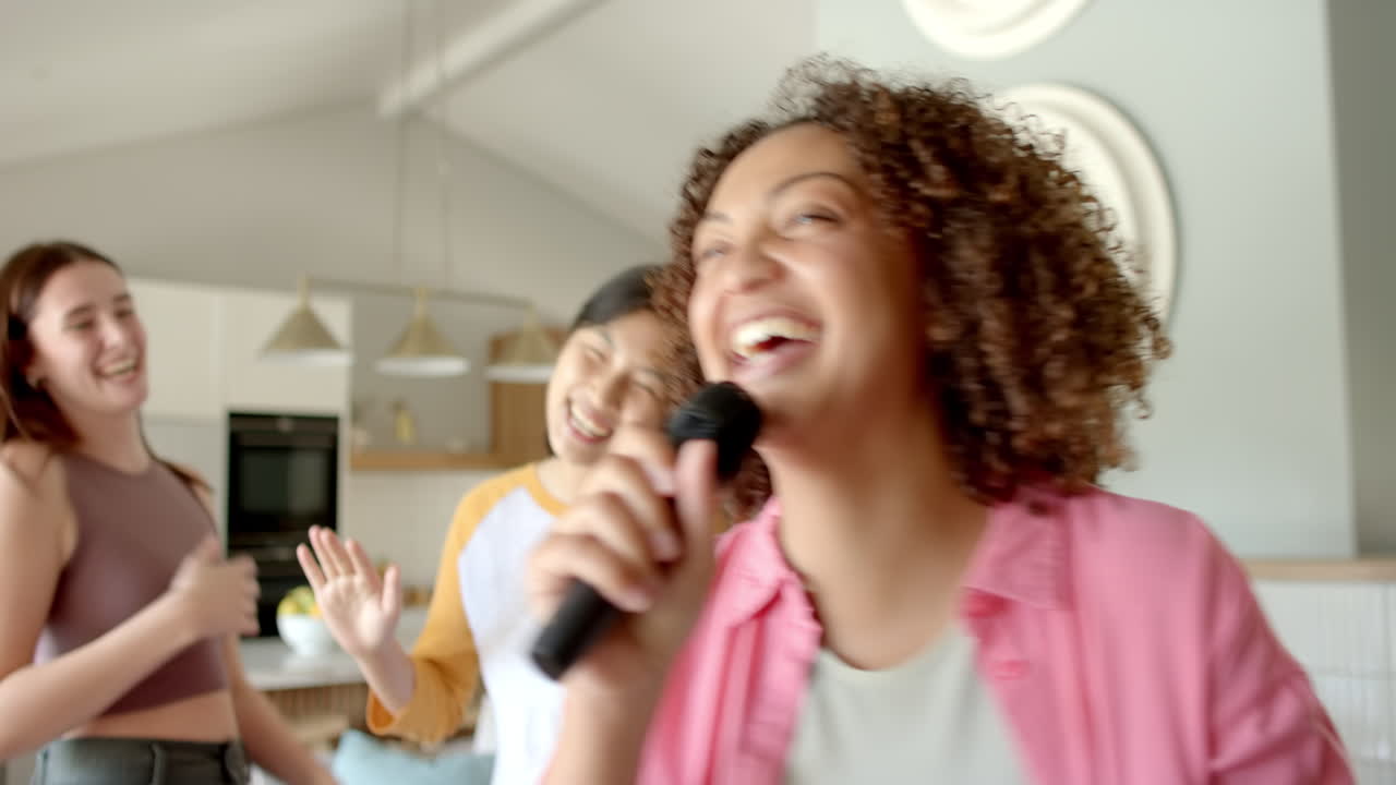 Singing into microphone, woman enjoying karaoke with friends at home party