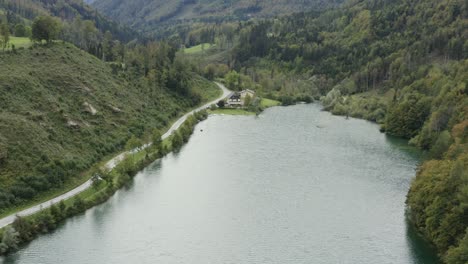 south shore of freibach reservoir dam in austria with stauseewirt greek eatery lodge at the far side, aerial approach tilt up view