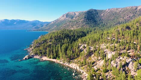 montañas de california en el lago taho con agua azul turquesa cristalina y playa con embarcadero de roca y exuberante bosque de pinos - toma aérea de drones